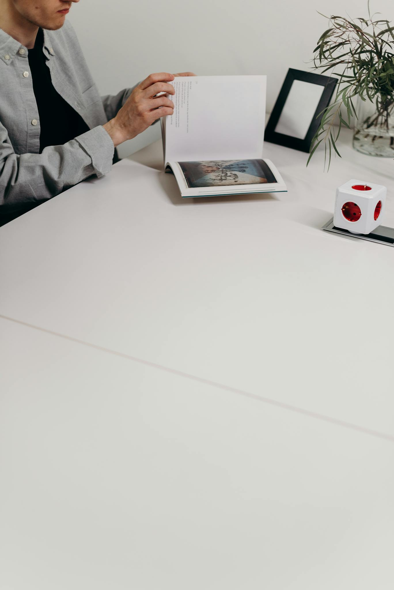 A person reading a book in a minimalist home office setting.